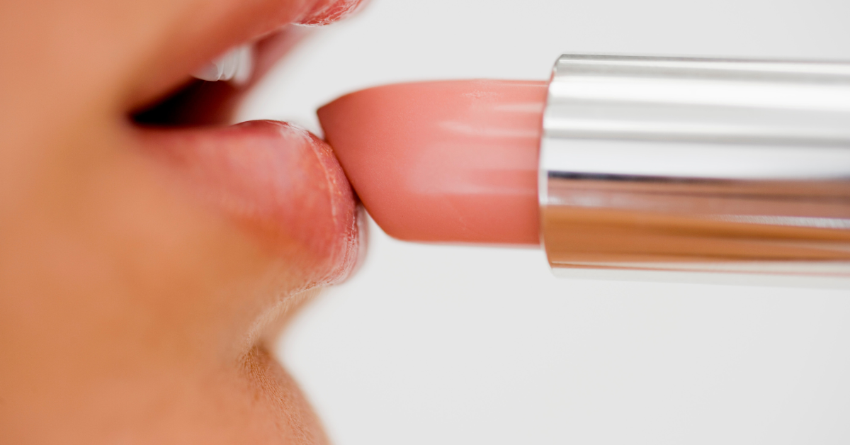 close up photo of a woman applying pink lipstick