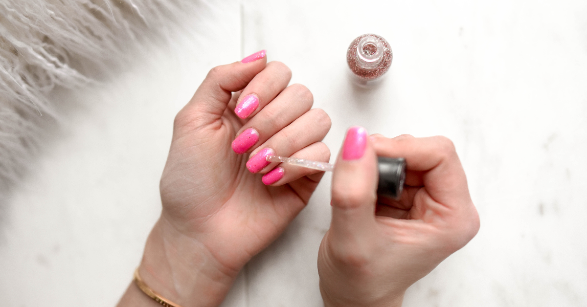 Close up image of woman painting her nails pink